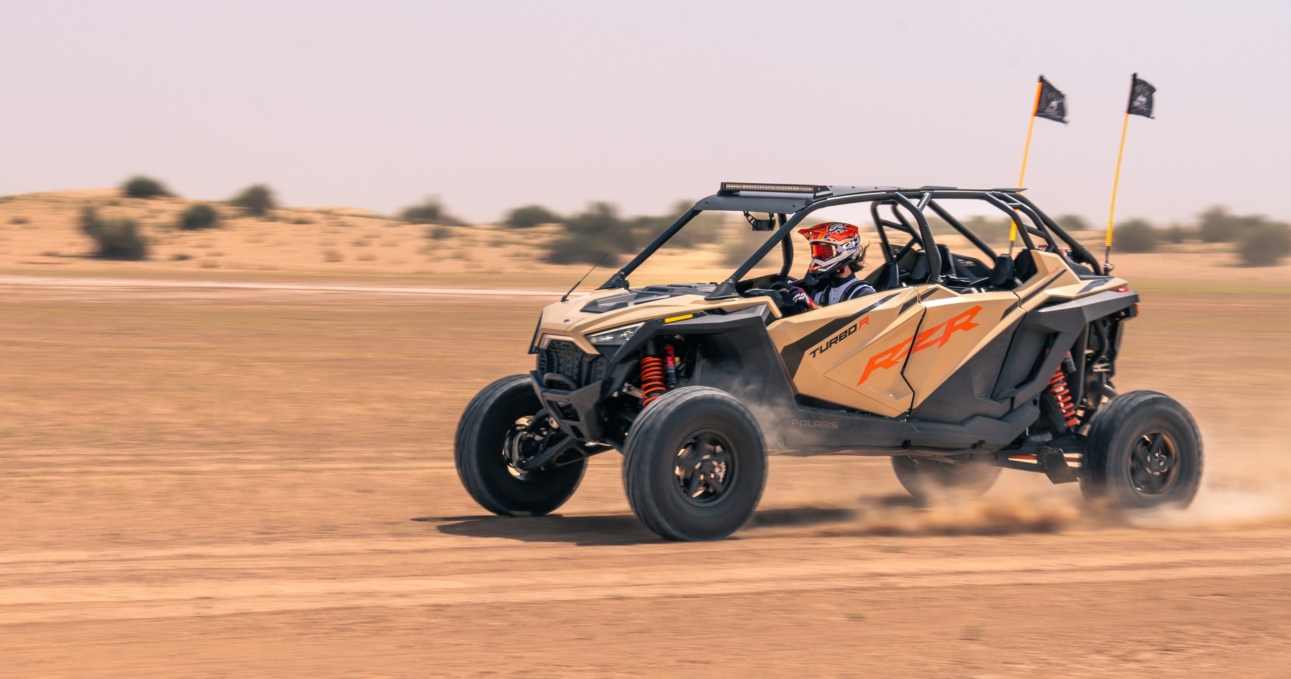 Off-road buggy driving fast on a desert track, dust trailing behind.
